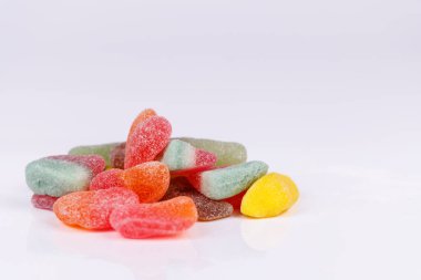 Beyaz bir yüzeye yığılmış çeşitli aromalı renkli şeker yığını şeker severler için canlı ve çiğnenebilir yiyeceklerin yakın görüntüsünü sunuyor.