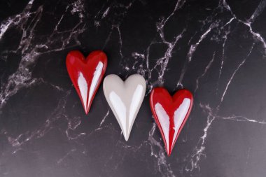 Porselenden yapılmış kırmızı ve beyaz kalpler siyah mermer bir masaya dizilir. Minimalist ama romantik bir Sevgililer Günü teması sunulur.