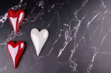 Kara mermer üzerine kurulmuş romantik kırmızı ve beyaz porselen kalpler Sevgililer Günü kutlamaları için aşkı ve zarafeti vurguluyor.