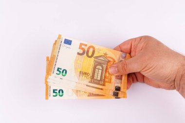Temiz beyaz bir yüzey üzerinde 50 avroluk banknotları tutan bir eli gösteren ve ekonomik gücü yansıtan baştan aşağı ilgi çekici bir bakış açısı