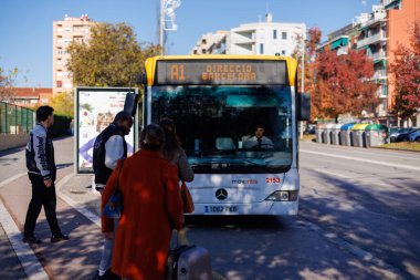 Barselona-İspanya, 28 de noviembre de 2024. Barcelona sokaklarının hareketli atmosferine girmeye hazırlanan bir belediye otobüsü kalabalık bir durakta duruyor.