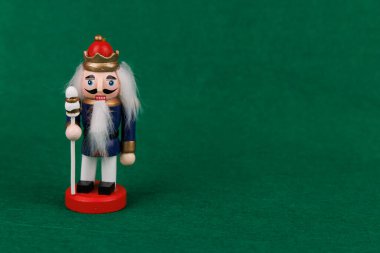 Neşeli, ahşap fındıkkıran, orijinal saçlı, yemyeşil bir arka planda, mevsimin neşeli ruhunu somutlaştırıyor.