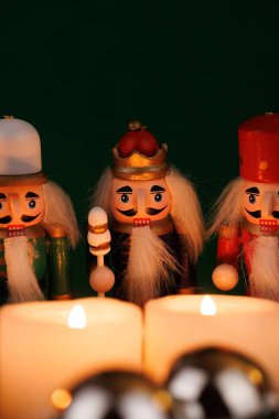 Orijinal saçlarla süslenmiş bu şakacı fındıkkıran, parlak yeşil bir arkaplanda yanan mumlar ve Noel süsleriyle kurulmuş.