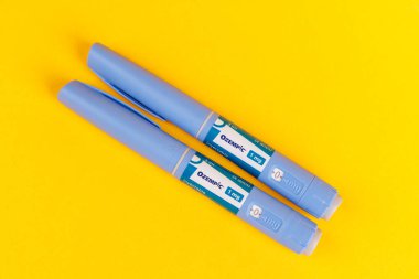 İspanya 'nın Barselona kentindeki Ozempic 1 ml' lik Sarı Arka plan İlaç Kalemleri Üst Görünümü, Semaglutide ve Enjeksiyon Aksesuarları