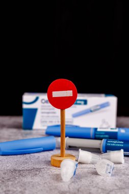 Semaglutide ilaç kalemleri ve çimento masasının üzerinde diyabet yönetimi araçlarını vurgulayan tahta giriş yasak tabelası.