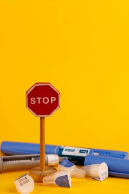 Glikoz kontrol kalemi, parlak sarı bir fonda küçük bir ahşap dur işaretinin yanında gösterilen semaglutid içeren.