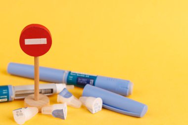 Tahta giriş işareti semaglutit içeren glikoz kontrol kalemi ile eşleştirilmiş, canlı sarı bir arka planda sergileniyor.