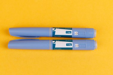 Glikoz kontrolü için kullanılan kalemler, parlak sarı bir arkaplanda gösterilen semaglutid ile tepeden tırnağa çekilmiş.