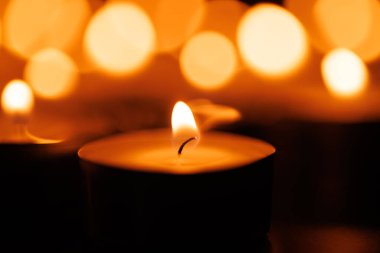 Kutsal hafta kutlamalarında inanç ve maneviyatı simgeleyen, siyah arka planda usulca parlayan bir mum seti.