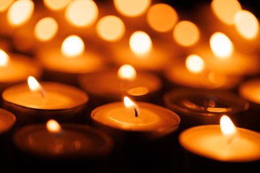 Kutsal hafta temalı parlak mumlar, karanlık arka planda parlıyor, barışı, inancı ve bağlılığı somutlaştırıyor.