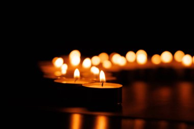 Tek bir mum odak noktasında durur. Arka planda, Paskalya maneviyatını sembolize eden yumuşak, parlak mumlar vardır.