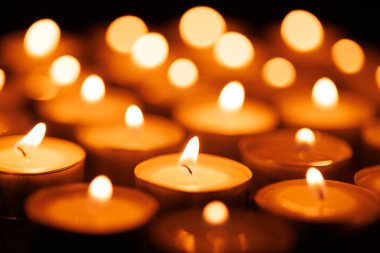 A set of candles burning on a dark background, expressing faith, hope, and reverence during the Holy Week season clipart