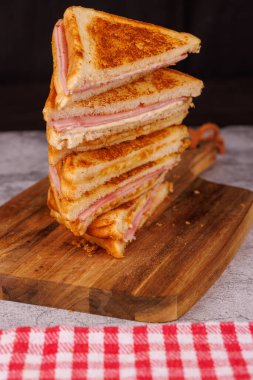 Lezzetli bir jambonlu ve peynirli sandviç seçimi dikey, güzel bir şekilde siyah arka planlı gri beton bir masada sunuldu.