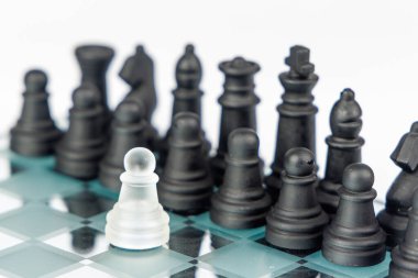 Satranç stratejisi ve meydan okuma yansıtıcı bir satranç tahtasında siyah taşlara bakan beyaz bir piyon tarafından tasvir edilir, kararlılık ve risk gösterir