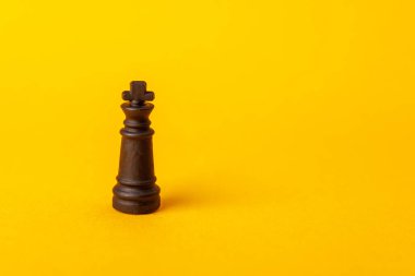 Satranç kralı, satranç ve karar verme oyununda strateji, liderlik ve gücü sembolize eden parlak sarı bir arka planda tek başına duruyor.