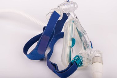 Bir CPAP solunum cihazı, kompakt tasarımlı, bir ekran, yumuşak yüz maskesi, ve temiz beyaz bir arkaplan üzerine kurulmuş bir hava tüpü