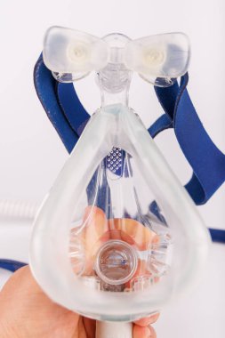 Solunum yardımı için yapılmış, sezgisel bir görüntü, yumuşak maske ve hava tüpü içeren beyaz bir CPAP makinesi.