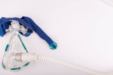 Apnesi olan hastalar için beyaz bir CPAP terapi cihazı, beyaz bir arka plana yerleştirilmiş bir ekran, maske ve tıbbi boru içeriyor.