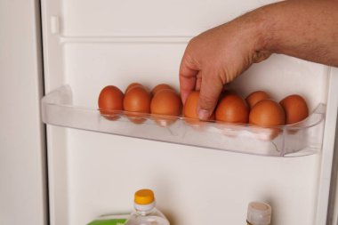 Buzdolabının içindeki yumurtaya uzanan bir el, artan gıda fiyatları ve ekonomik enflasyonun etkisini vurguluyor..