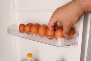 Buzdolabından yumurta toplayan bir el, artan gıda fiyatları ve ekonomik zorlukları temsil ediyor.