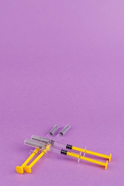 Heparin dolu bir grup cam şırınga klinik tarzda mor bir arkaplanda duruyor.