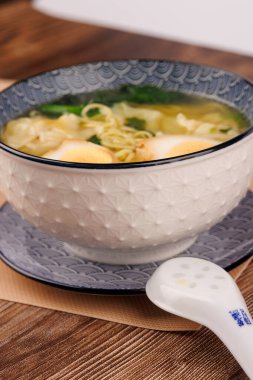 Yumurtalı ramen eriştesi, wonton ve seramik kaşık..