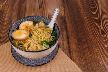 Japon eriştesinin kaşık, wonton ve yumurtalı üst tabaka görüntüsünü davet ediyorum..