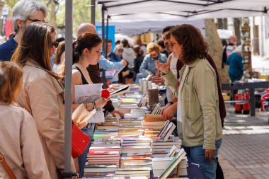 Barselona-İspanya, 23 Nisan 2025. La Rambla, San Jordi 'nin edebiyat merkezi oldu. Ziyaretçiler kitapları karıştırırken güller ve buğdaylar şenlikli cazibe katıyor.