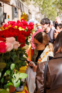 Barselona-İspanya, 23 Nisan 2025. Yerel halk, kültür ve aşk dolu bir gün olan Sant Jordi 'deki kitap ve güllere hayran..