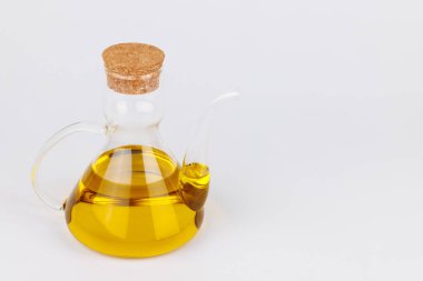 Beyaz yüzeyde zeytinyağlı cam bir kap duruyor. Akdeniz mutfağı, diyet ve ürün kullanımı için ideal.