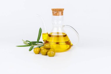 Parlak beyaz bir yüzey üzerinde yeşil zeytin ve yapraklı zeytin dallarının yanında temiz zeytin yağı kabuğu