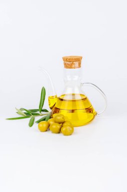 Yeşil zeytinli ve beyaz zemin üzerinde zeytin filizi bulunan Rustik cam şişe.