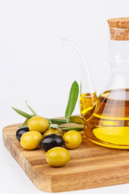 İçinde zeytin yağı, yeşil zeytin ve zeytin yaprakları olan cam bir şişe. Geleneksel Akdeniz elementleriyle organik gıda kavramı.