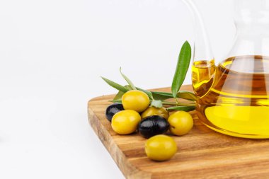 Akdeniz 'de zeytinyağı, zeytin ve zeytin dalları ile ahşap bir kesme tahtasına dizilmiş. Doğal ve sağlıklı besin maddeleri.