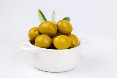 Seramik kasede ve zeytin dalında düz yeşil zeytin yatağı, minimum ve doğal gıda kurulumu.