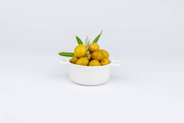 Zeytin dallı yeşil zeytin kabının içindeki havadan çekilen resim, beyaz zemin üzerinde Akdeniz yemekleri konsepti..