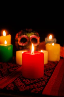 Manolyalarla çevrili zarif kafatası siyaha boyanmış ve geleneksel sunağın bir parçası olarak mumlar yakılmış.