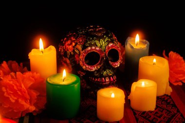 Çiçekler ve mumlarla çevrili anlamlı bir siyah kafatası geleneksel bir Meksika anıtı oluşturuyor.
