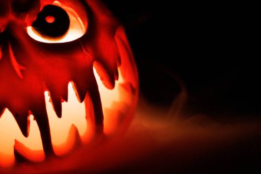 Korkunç Cadılar Bayramı balkabağı. Arka planda dumanla parlıyor..