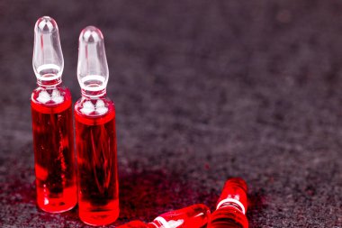 Sağlık ve refah için siyah yüzeyde gösterilen kırmızı B12 vitamini ampulleri