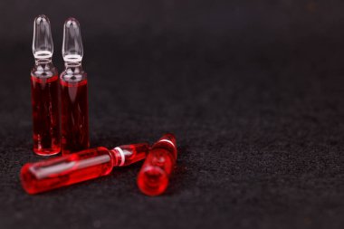 Siyah arka plana yerleştirilmiş B12 vitamini kırmızı ampulleri terapi ve sağlık desteğini gösteriyor