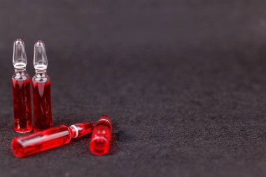 Siyah arkaplanda düzgünce düzenlenmiş kırmızı B12 ampulleri takviye terapisi gösteriyor