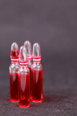 Koyu zemin üzerinde kırmızı B12 vitamin ampulleri terapi ve beslenme bakımını yansıtıyor