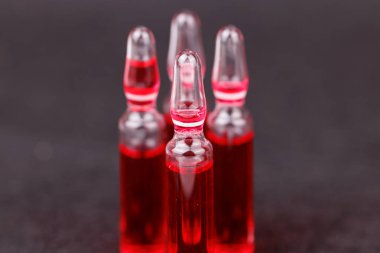 Koyu arkaplandaki kırmızı B12 vitamin ampulleri satırı takviyeyi temsil ediyor