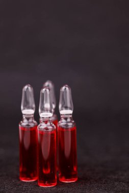 Siyah yüzeyde sağlık ve bakım için simetrik kırmızı B12 ampulleri