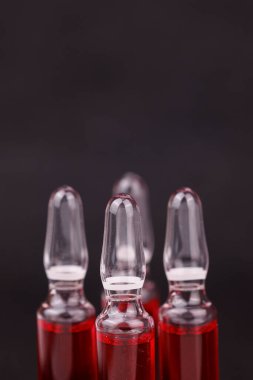 Siyah arkaplanda tıbbi destek gösteren kırmızı B12 ampullerini kapat