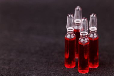 Siyah arkaplandaki cam kırmızı B12 ampulleri tıbbi bakımı temsil ediyor