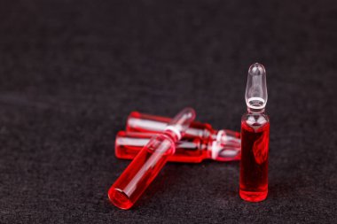 Klinik ve sağIık kavramı için kırmızı B12 cam ampulleri siyah zemin üzerinde izole.