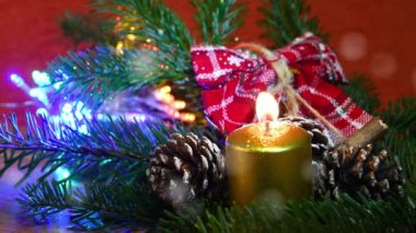 Yeşil köknar ağacında çam kozalaklı altın mum. Arka planda parlak ışıklar ve dekor var. Yağan karın etkisi, Xmas Tatil atmosferi.