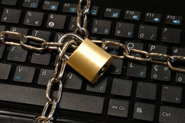Computer security concept with an iron chain and padlock on the laptop keyboard